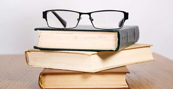 Image of glasses on a pile of books. 