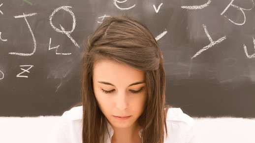 Image of a teenage girl looking down with a chalkboard behind her.