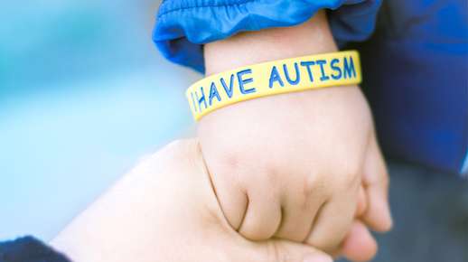 Image of a child's hand wearing an autism bracelet. 