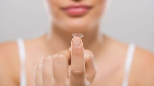 Image of a woman holding a contacts lens. 