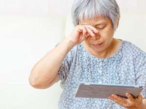 Image of an elderly woman rubbing her eyes.