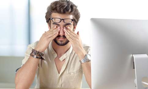 Man rubbing eyes after looking at computer screen